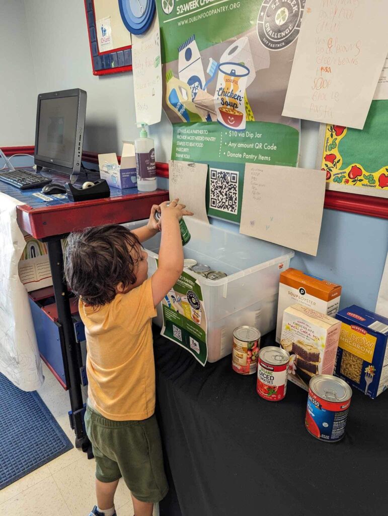 Little boy donating canned goods to the Dublin Food Pantry during a summer of giving.